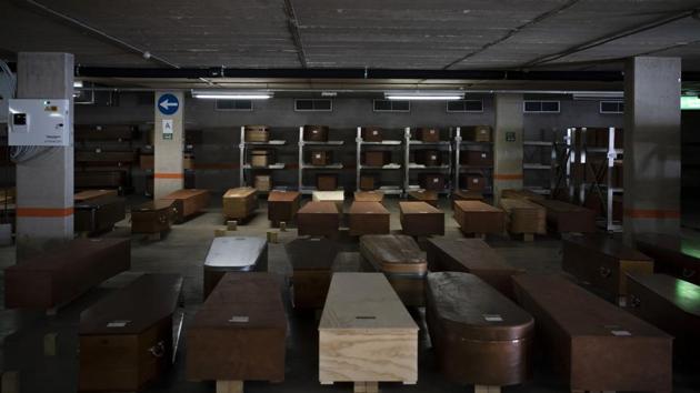 Coffins carrying the bodies of COVID-19 victims waiting to be buried or cremated are held at the Collserola funeral home. The space run by the Memora funeral home group has been equipped with air conditioning to preserve the dead as coffins in waiting pile up. (Felipe Dana / AP) Coffins carrying the bodies of COVID-19 victims waiting to be buried or cremated are held at the Collserola funeral home. The space run by the Memora funeral home group has been equipped with air conditioning to preserve the dead as coffins in waiting pile up. (Felipe Dana / AP)