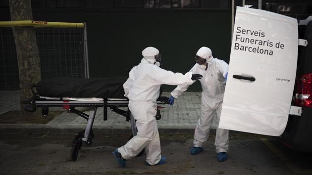 Funeral home workers pick up the body of a suspected COVID-19 victim from a nursing home in Barcelona, Spain. Now, infected corpses cannot be removed from their sealed body bags and are placed straight into coffins, something Fernandez and his team try to do with the utmost care. (Felipe Dana / AP) Funeral home workers pick up the body of a suspected COVID-19 victim from a nursing home in Barcelona, Spain. Now, infected corpses cannot be removed from their sealed body bags and are placed straight into coffins, something Fernandez and his team try to do with the utmost care. (Felipe Dana / AP)