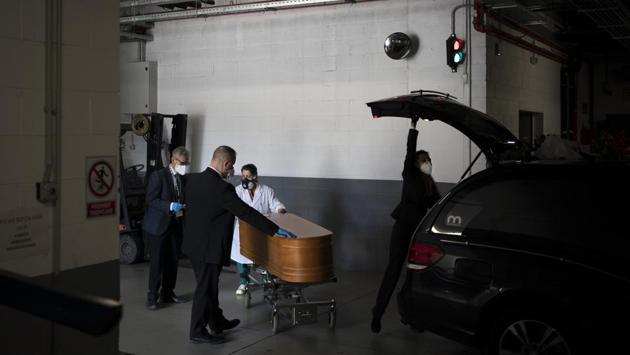 Workers prepare to transport a coffin at the Sancho de Avila funeral home in Barcelona. The demand for cremations is so great in Barcelona that even with all four of the city’s ovens operating 24/7, officials considered the option of placing the dead in temporary plots. Meanwhile, in cemeteries authorities have limited people attending funerals to three. (Felipe Dana / AP) Workers prepare to transport a coffin at the Sancho de Avila funeral home in Barcelona. The demand for cremations is so great in Barcelona that even with all four of the city’s ovens operating 24/7, officials considered the option of placing the dead in temporary plots. Meanwhile, in cemeteries authorities have limited people attending funerals to three. (Felipe Dana / AP)