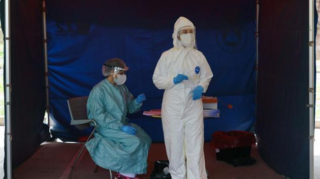 Healthcare workers dressed in protective gear wait for drivers at a drive-through testing point for the Covid-19 disease at the University Hospital in Burgos, Spain, on April 18, 2020. (AFP) Healthcare workers dressed in protective gear wait for drivers at a drive-through testing point for the Covid-19 disease at the University Hospital in Burgos, Spain, on April 18, 2020. (AFP)