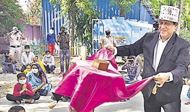 Magician Rajkumar performs for migrant workers and children at a shelter home in Lajpat Nagar.(PHOTO: Raj K Raj/HT)