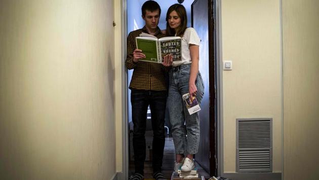 Emmanuel and his partner Aziliz pose among piles of books at the entrance door of their apartment, in Paris. Others manage to work on plans kept on hold. (Elena Fusco / AFP)