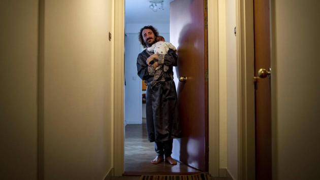 Thierry holds his newborn and smiles as he stands at the entrance of his apartment in Boulogne-Billancourt, on the outskirts of Paris. Some have their hands full at home. (Elena Fusco / AFP)