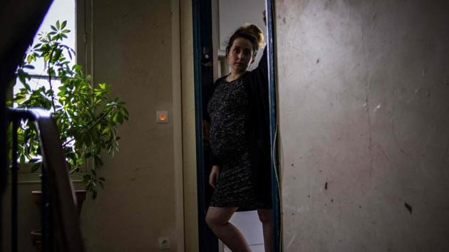 Aurore, an expecting mother poses by the entrance door of her apartment in Paris. Pregnant with twins, she admitted to spending most of her time sleeping. (Elena Fusco / AFP)