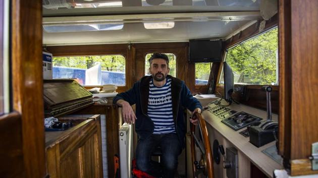 Charles, sits on a chair in the captain’s cabin aboard a barge boat where he lives, in Paris. Not everyone loses out on a view of the outdoors. (Elena Fusco / AFP)