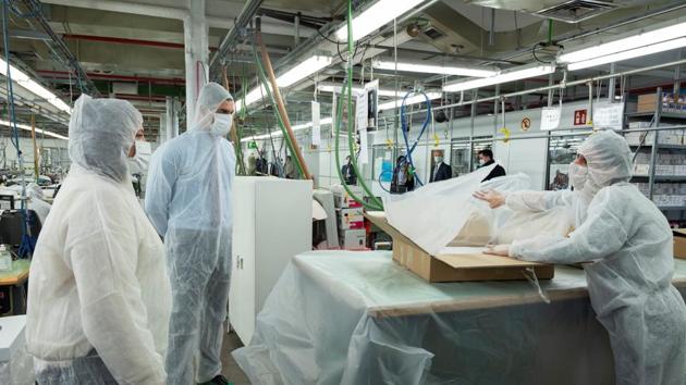 Spanish Prime Minister Pedro Sanchez wearing a full protective suit and a mask looks at people working during a visit at El Corte Ingles retail store sewing workshop amid the coronavirus disease (COVID-19) outbreak in Madrid, Spain.(via REUTERS)