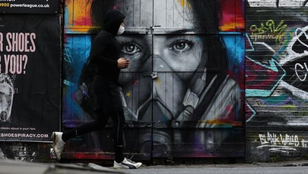 A man wearing a protective face mask runs by graffiti in Brick Lane as the spread of the coronavirus disease continues in London, Britain. (Reuters Photo) A man wearing a protective face mask runs by graffiti in Brick Lane as the spread of the coronavirus disease continues in London, Britain. (Reuters Photo)