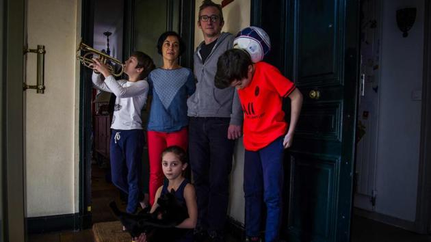 Sonia and her husband Marco pose with their children Celestin, Auguste and Lazarine by the entrance of their apartment, in Paris. (Elena Fusco / AFP)