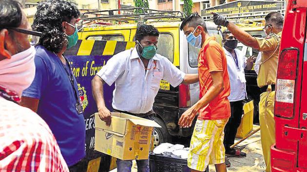 BMC staff distribute food to residents of Dharavi amid the Covid-19 pandemic in Mumbai on Sunday.(ANSHUMAN POYREKAR/HT PHOTO.)