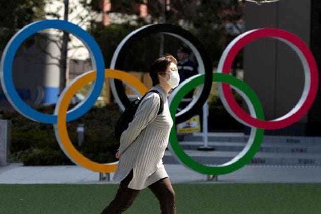 A woman wearing a protective face mask, following an outbreak of the coronavirus disease (COVID-19), walks past the Olympic rings in front of the Japan Olympics Museum in Tokyo.(REUTERS)