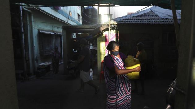 Mina Jakhawadiya carries a water can after filing it from a public tap. Jakhawadiya makes a living selling cheap plastic goods with her husband on the streets of Mumbai. For her, the order meant 21 days in a 6-by-9 foot room with five people, no work, a couple days of food and very little cash. (Rafiq Maqbool / AP)