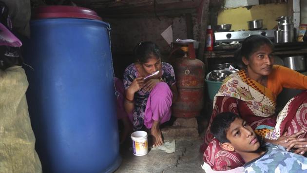 Mina Jakhawadiya, with her son Ritik Ramesh in her lap watches the news as her daughter Guddi Ramesh brushes her teeth in their house. Jakhawadiya recalled to new agency AP, feeling afraid for the days to come as she looked at the speech on their little television, spattered with stickers left over the years by one child or another. (Rafiq Maqbool / AP)