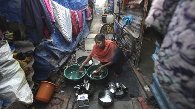 Mina’s daughter Guddi Ramesh washes utensils outside their home. Members of the gang who run the neighbourhood had come by a few times for their monthly rent, which was due on April 1. But the family didn’t have the money. (Rafiq Maqbool / AP)