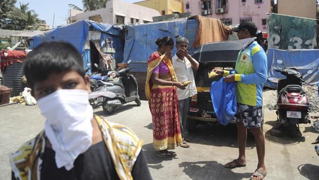 Mina Jhawadiya with her husband Ramesh Karsan (C) as they receive free food packets during a distribution. Those near the top can hunker down in gated apartment complexes and order food deliveries online. But not Jakhawadiya. Aid groups were distributing enough food every few days to keep the worst hunger at bay. (Rafiq Maqbool / AP)