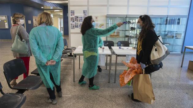 Cristina Settembrese has her temperature checked by colleagues at the Hospital. For healthcare workers like Settembrese who spend their days caring for COVID-19 patients in a hospital ward, finally heading home after a shift signals a personal isolation that is also a necessary precaution. (Luca Bruno / AP) Cristina Settembrese has her temperature checked by colleagues at the Hospital. For healthcare workers like Settembrese who spend their days caring for COVID-19 patients in a hospital ward, finally heading home after a shift signals a personal isolation that is also a necessary precaution. (Luca Bruno / AP)