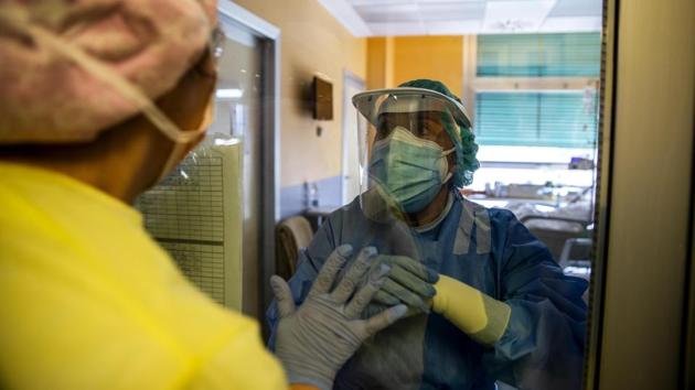 Cristina Settembrese speaks to a colleague through a window in the ward. All of a sudden, she had to learn how to operate machines she likens to “helmets” to help patients breathe. She studied the operating instructions at home in a kind of self-taught cram course. (Luca Bruno / AP) Cristina Settembrese speaks to a colleague through a window in the ward. All of a sudden, she had to learn how to operate machines she likens to “helmets” to help patients breathe. She studied the operating instructions at home in a kind of self-taught cram course. (Luca Bruno / AP)
