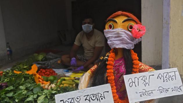 A vegetable vendor waits for customers in a stall next to a mythical figure holding placards to raise awareness about the current pandemic during a government-imposed nationwide lockdown as a preventive measure against the coronavirus (COVID-19), in Kolkata on April 21. Vegetable prices have soared across India, and the lockdown has made it hard for vendors to carry out business, because of movement restrictions. (Dibyangshu Sarkar / AFP) A vegetable vendor waits for customers in a stall next to a mythical figure holding placards to raise awareness about the current pandemic during a government-imposed nationwide lockdown as a preventive measure against the coronavirus (COVID-19), in Kolkata on April 21. Vegetable prices have soared across India, and the lockdown has made it hard for vendors to carry out business, because of movement restrictions. (Dibyangshu Sarkar / AFP)