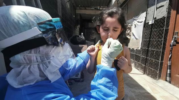 A member of a medical team that works with mobile coronavirus disease (COVID-19) testing units wears protective gear as he takes a swab from a child to track new cases of COVID-19, in Najaf, Iraq April 21,2020. Picture taken April 21,2020. REUTERS/Ahmed Saed(REUTERS)