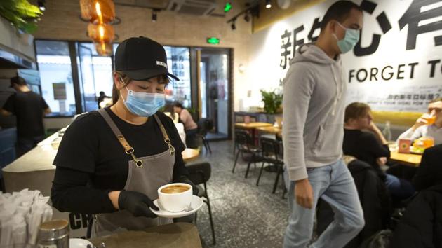 A server wearing a face mask carries food in a Beijing eatery. (AP) A server wearing a face mask carries food in a Beijing eatery. (AP)
