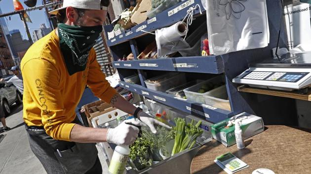Derek Tigue sprays water on vegetables outside FGM General Store, in New York. The bar saw a neighbourhood need and went to work, replacing the tables and chairs with shelving and refrigerators stocking produce and household essentials. (Kathy Willens / AP) Derek Tigue sprays water on vegetables outside FGM General Store, in New York. The bar saw a neighbourhood need and went to work, replacing the tables and chairs with shelving and refrigerators stocking produce and household essentials. (Kathy Willens / AP)