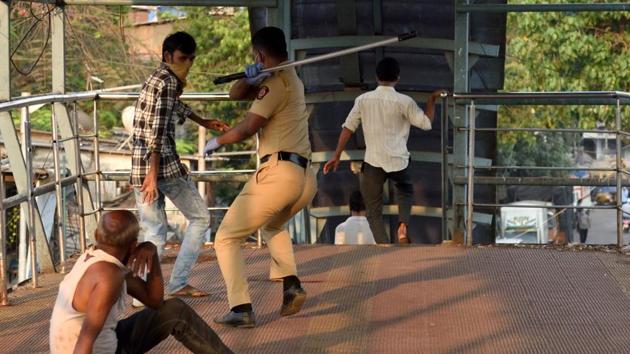 A policeman hits a man violating the lockdown, on Mahim skywalk on Tuesday. (Satish Bate/HT Photo) A policeman hits a man violating the lockdown, on Mahim skywalk on Tuesday. (Satish Bate/HT Photo)