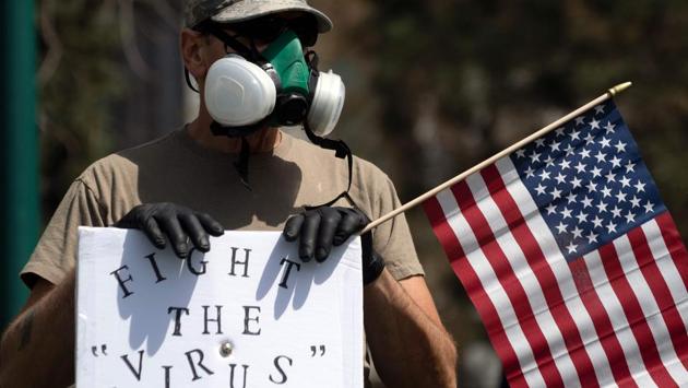 A demonstrator wearing a respirator mask and holding a US flag gathers with others to protest coronavirus stay-at-home orders during a “ReOpen Colorado” rally in Denver, Colorado, on April 19. The coronavirus has infected almost 820,000 people in the United States and killed over 45,000 - the world’s highest number of cases and deaths. (Jason Conolly / AFP) 