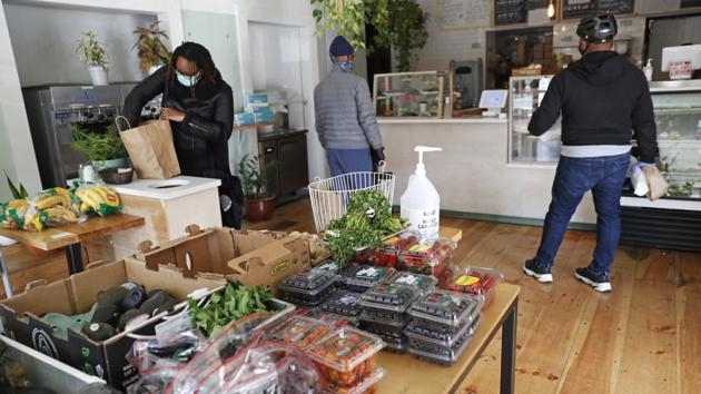 A customer bags her groceries as others wait to pay after shopping for fresh produce, bread and other items, at Clementine Bakery. The popular neighbourhood spot removed cafe tables and replaced them with a larger table to display fresh fruits and vegetables for sale. Half the bakery now resembles a small farmer’s market. (Kathy Willens / AP) A customer bags her groceries as others wait to pay after shopping for fresh produce, bread and other items, at Clementine Bakery. The popular neighbourhood spot removed cafe tables and replaced them with a larger table to display fresh fruits and vegetables for sale. Half the bakery now resembles a small farmer’s market. (Kathy Willens / AP)