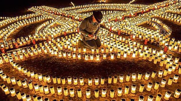 Gertrud Schop, a tax adviser, lights candles forming a giant cross in memory of Covid-19 victims in Zella-Mehlis in Germany. Schop lit about 4,000 candles, which took seven hours to complete.(AP)