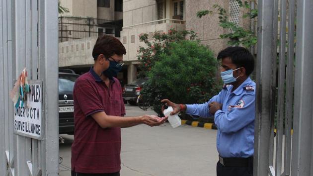 A security guard offers hand sanitizer to a resident Rail Vihar Sector 47 during lockdown, in Gurugram(Yogendra Kumar/HT PHOTO)