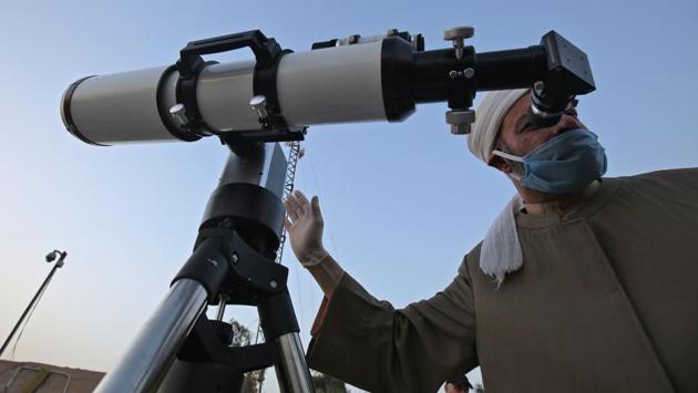 A Sunni Muslim cleric wearing a face mask uses a telescope to scan for the crescent moon, which if sighted would mark the beginning of the month of Ramzan, at the Abu al-Hanifa al-Numan mosque in Iraq's capital Baghdad on April 22. Muslims globally are bracing for a bleak month of Ramzan fasting as the threat of COVID-19 lingers. (Ahmad Al-Rubaye / AFP) A Sunni Muslim cleric wearing a face mask uses a telescope to scan for the crescent moon, which if sighted would mark the beginning of the month of Ramzan, at the Abu al-Hanifa al-Numan mosque in Iraq's capital Baghdad on April 22. Muslims globally are bracing for a bleak month of Ramzan fasting as the threat of COVID-19 lingers. (Ahmad Al-Rubaye / AFP)