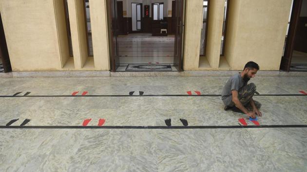 A man places stickers of feet silhouettes on the floor of a mosque to maintain social distance during gatherings during Ramzan in Karachi on April 23. The restrictions on gatherings and observances have also garnered pushback from clerics viewing them as attempts to shrink the number of people going to mosques. (Asif Hassan / AFP) A man places stickers of feet silhouettes on the floor of a mosque to maintain social distance during gatherings during Ramzan in Karachi on April 23. The restrictions on gatherings and observances have also garnered pushback from clerics viewing them as attempts to shrink the number of people going to mosques. (Asif Hassan / AFP)