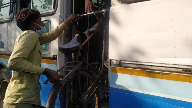 A migrant labourer loading his bicycle onto a Haryana Roadways bus in Yamunanagar on Saturday(HT PHOTO)