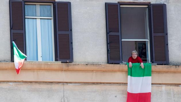 A resident in the Garbatella district of Rome joins the 'Liberation Day' flashmob on April 25 from her window. Locked down Romans sang an anti-Fascist resistance song out of windows Saturday as Italy celebrated the 75th anniversary of its liberation by Allied forces during World War II. (Tiziana Fabi / AFP)