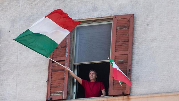 A resident waves the Italian flag in the Garbatella district of Rome on April 25 during a 'Liberation Day' flashmob with people singing the Italian partisan song 'Bella Ciao' from their windows during the country's lockdown aimed at curbing the spread of the COVID-19 infection. (Tiziana Fabi / AFP)