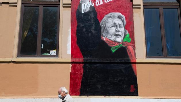 A man wearing a face mask walks past mask a mural of late Italian anti-fascist and syndicalist Tina Costa, on April 25 in the San Lorenzo district of Rome, on the 75th anniversary of Liberation Day. (Tiziana Fabi / AFP)