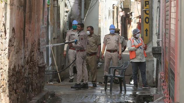 Police and health officials sanitize a congested lane after a resident tested positive for Covid-19, outside Ramganj locality in Jaipur on Sunday.(Himanshu Vyas/HT PHOTO)