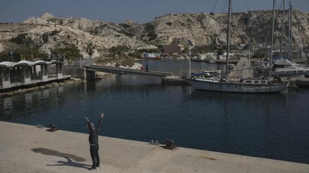 A ferry boat crew member stretches on the deserted Frioul port before departing for Marseille. Now, amid the coronavirus lockdown and with no tourists, the islands’ few residents again feel cut off, left to fend largely for themselves. (Daniel Cole / AP) A ferry boat crew member stretches on the deserted Frioul port before departing for Marseille. Now, amid the coronavirus lockdown and with no tourists, the islands’ few residents again feel cut off, left to fend largely for themselves. (Daniel Cole / AP)
