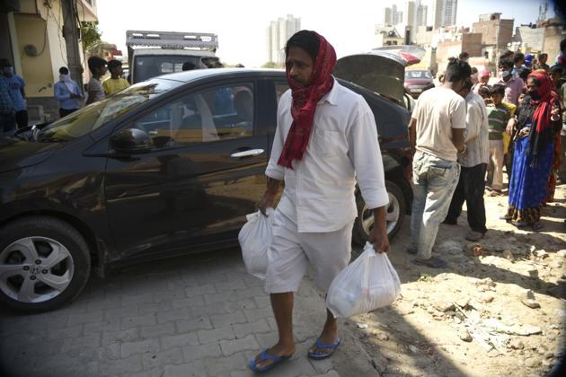 A man with provisions handed to him by a GNEM volunteer in Gurgaon.(Parveen Kumar/HT Photo)