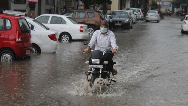 A motorcyclist wades pass a waterlogged street after heavy rain in Patel Nagar, Gurugram, on April 26. In Delhi and the National Capital Region, below normal temperatures have meant pleasant days and mildly cool nights. (Yogendra Kumar / HT Photo)