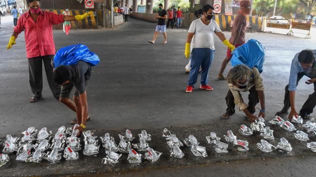 Homeless people pick up food packets kept on the sidewalk by local residents for people in need during the government-imposed nationwide lockdown in Mumbai. (Indranil Mukherjee / AFP) Homeless people pick up food packets kept on the sidewalk by local residents for people in need during the government-imposed nationwide lockdown in Mumbai. (Indranil Mukherjee / AFP)