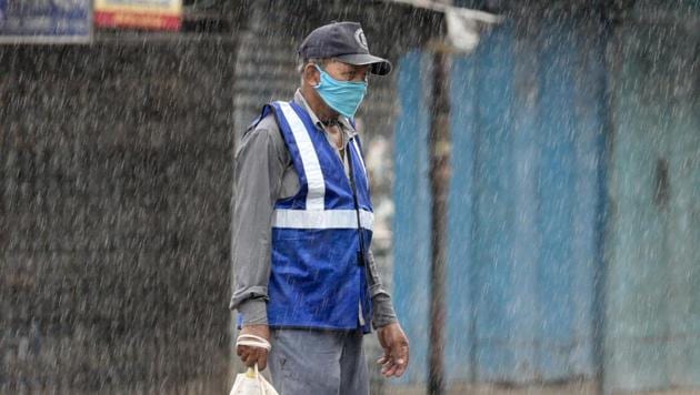 A man wearing facemask seen during light rainfall at Manicktala crossing in Kolkata, West Bengal. (Samir Jana/HT Photo)