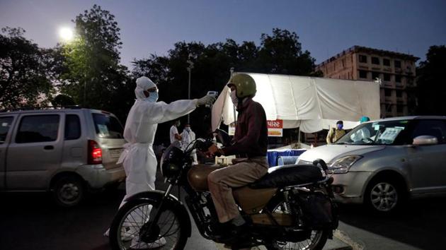 A health worker uses an infrared thermometer to measure the temperature of a motorcyclist on a road during a nationwide lockdown to slow the spreading of the coronavirus disease (COVID-19) in Ahmedabad, India. (REUTERS)