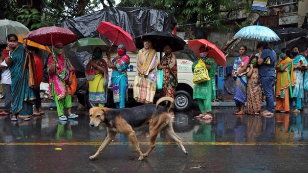 A stray dog walks past women waiting in a queue at a grocery distribution as it rains during the lockdown, in Kolkata on April 27. No heat waves have been recorded so far except in isolated pockets of Gujarat and Marathwada (and only for a day in both), which is unusual for this time of the year. (Rupak De Chowdhuri / REUTERS)