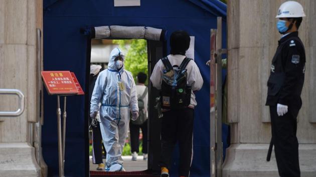 An official in a hazmat suit waits inside a high school entrance as a student arrives in Beijing. China has largely curbed the spread of the deadly disease, but is still on high alert with growing fears of imported cases and a second wave of domestic infections in the northeast. (Greg Baker / AFP)