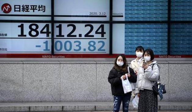 Women stand in front of at an electronic stock board showing Japan's Nikkei 225 index at a securities firm in Tokyo Thursday, March 12, 2020.(AP)