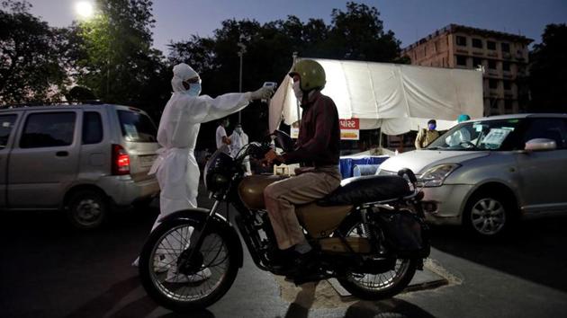 A health worker uses an infrared thermometer to measure the temperature of a motorcyclist on a road during a nationwide lockdown to slow the spreading of the coronavirus disease (COVID-19) in Ahmedabad.(REUTERS)