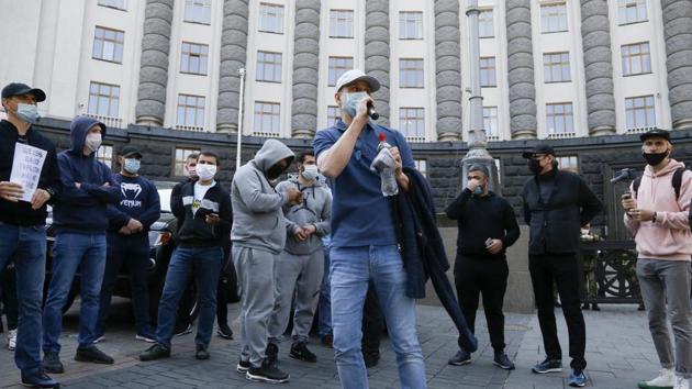 Wearing surgical masks, demonstrators briefly blocked traffic outside a government building in the city centre in defiance of rules against public gatherings. (AP) Wearing surgical masks, demonstrators briefly blocked traffic outside a government building in the city centre in defiance of rules against public gatherings. (AP)
