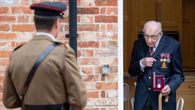 In a handout picture released by the British Ministry of Defence (MOD) on April 30, Captain Tom Moore (R), a former British Army Officer is presented by Colonel Thomas Miller with the Yorkshire Regiment Medal after being promoted to Honorary Colonel by Royal assent on his 100th birthday in Marston, Moretaine. (Robert Weidemar / MOD / AFP) In a handout picture released by the British Ministry of Defence (MOD) on April 30, Captain Tom Moore (R), a former British Army Officer is presented by Colonel Thomas Miller with the Yorkshire Regiment Medal after being promoted to Honorary Colonel by Royal assent on his 100th birthday in Marston, Moretaine. (Robert Weidemar / MOD / AFP)