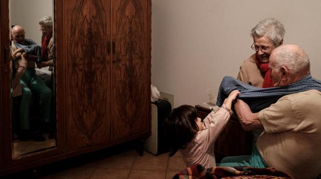 Ines Prandini, helps her husband Gino Verani, 87, get ready for bed, with the help of their great-granddaughter Bianca Toniolo, The family range in age from Bianca to her great-grandfather Gino. The experience has tested bonds of love under the stress of cohabitation, and Toniolo believes they have passed the test. (Marzio Toniolo via REUTERS) Ines Prandini, helps her husband Gino Verani, 87, get ready for bed, with the help of their great-granddaughter Bianca Toniolo, The family range in age from Bianca to her great-grandfather Gino. The experience has tested bonds of love under the stress of cohabitation, and Toniolo believes they have passed the test. (Marzio Toniolo via REUTERS)