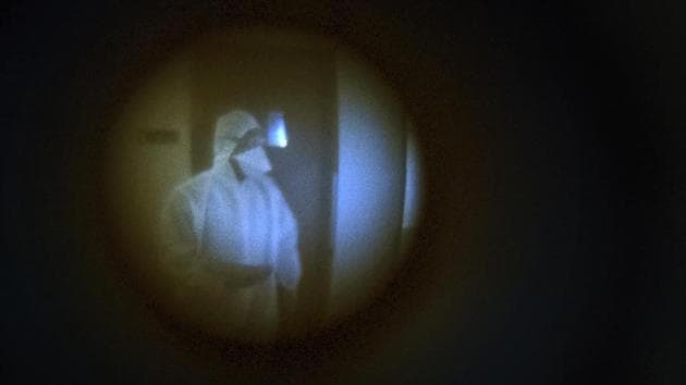 A civic worker seen through the peephole of Associated Press photographer Rafiq Maqbool's room, as he waits to fill a swab test form, at the hotel where Maqbool was in quarantine along with dozens of other journalists in Mumbai, on April 24, 2020. He had to leave his wife and children home alone to deal with a sealed building, anxious relatives and the stigma of being related to someone who had caught the virus. (Rafiq Maqbool / AP) A civic worker seen through the peephole of Associated Press photographer Rafiq Maqbool's room, as he waits to fill a swab test form, at the hotel where Maqbool was in quarantine along with dozens of other journalists in Mumbai, on April 24, 2020. He had to leave his wife and children home alone to deal with a sealed building, anxious relatives and the stigma of being related to someone who had caught the virus. (Rafiq Maqbool / AP)